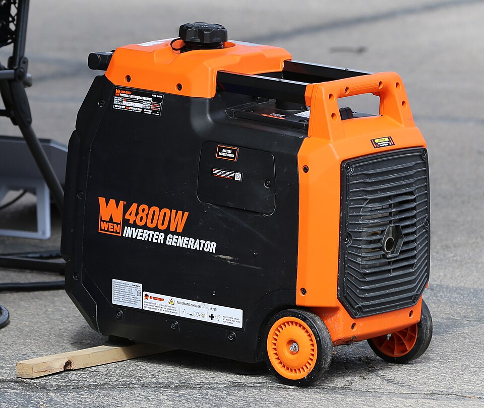 An orange and black WEN 4800 inverter generator with wheels, sitting on pavement, for storm prep in Coralville, IA